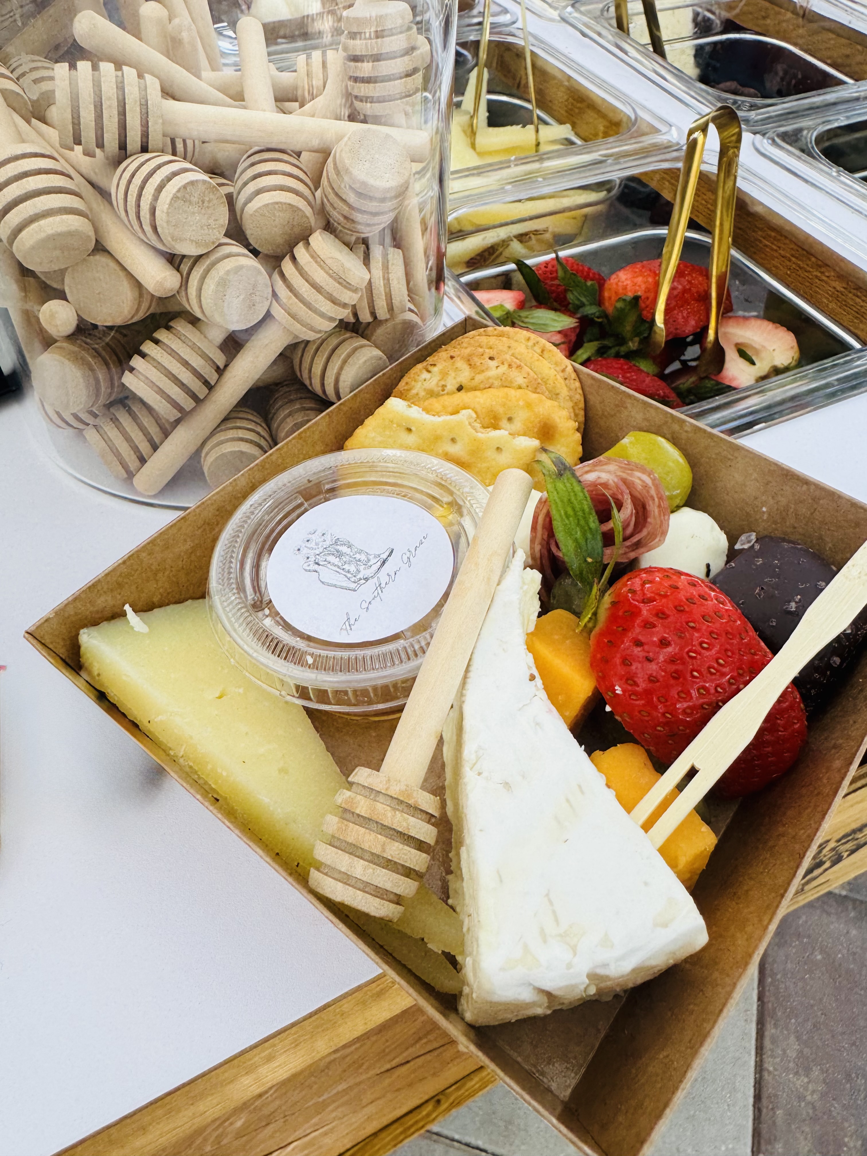 Beautifully arranged charcuterie board with cheese, crackers, fruit, and wooden serving utensils